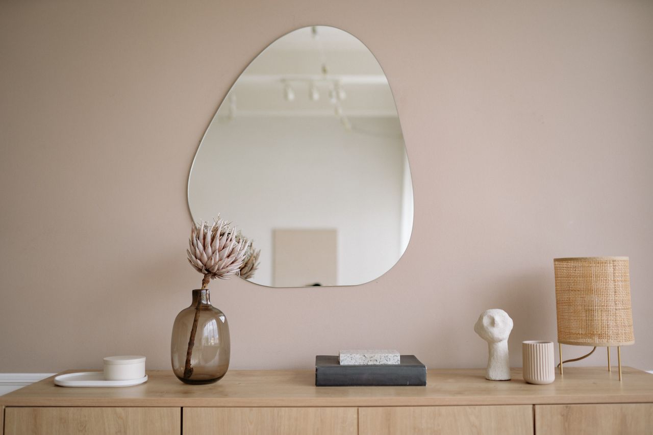 Intérieur minimaliste élégant avec un miroir, un vase décoratif et une lampe.